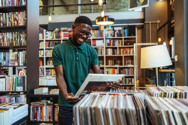 Young man holding vinyl record disk in the store during the day.