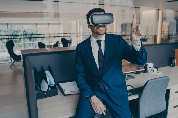 istock Businessman sitting on desk in office and using VR headset on his head, pointing with forefinger 1466620611