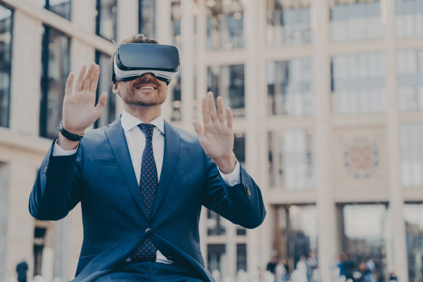 istock Young happy bearded man office worker dressed formally sitting outdoors and using VR headset or 3d goggles 1466620781