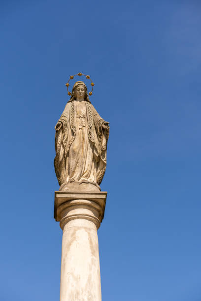 istock Classical sculpture of Holy Mary on a tall column in a clear blue sky 1466624404
