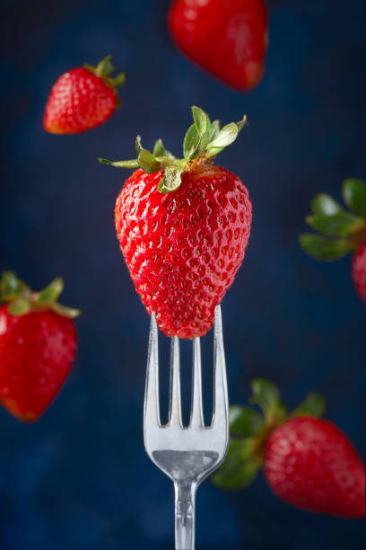 istock Vertical shot of a strawberry on a for against a blue blurry background 1466624607