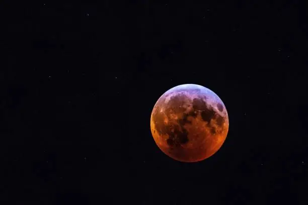 This image features a breathtaking view of a lunar eclipse, with the blood moon in full view