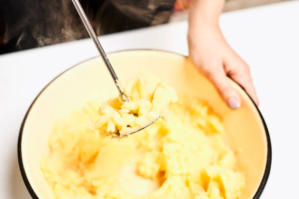 Mashed potatoes with butter and fresh white potatoes on background, wooden table. Healthy food.