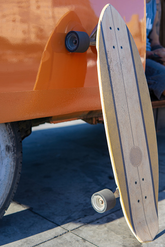 Close up view of an Isolated surfskate skateboard leaning on a vintage van