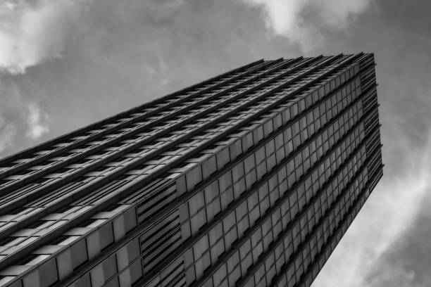 istock Grayscale low angle shot of a tall skyscraper with a cloudy sky above it 1466630002