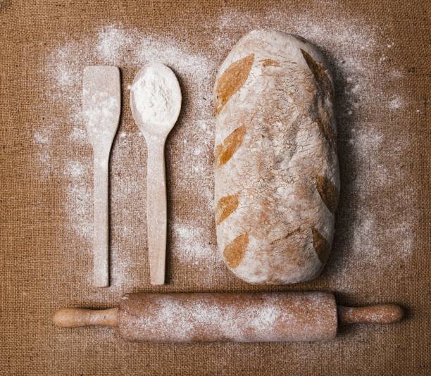 Bread and a wooden spoon on a brown surface with flour