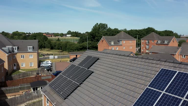 Aerial drone footage of a British house with solar panels on the roof, on a sunny summers day.