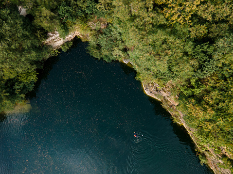 A deep lake surrounded by a cliff and dense forest