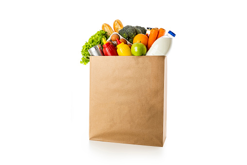 Front view of a paper shopping bag full of groceries isolated on white background.