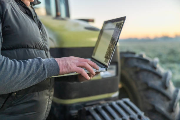istock Close-up male farmer,working on his laptop while standing outdoors next to his tractor on an agricultural field in the evening 1466634093