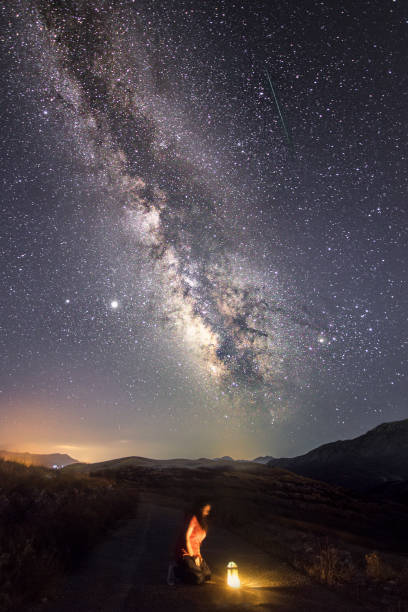 istock Woman kneeling on the road facing a light under a starry night 1466635290