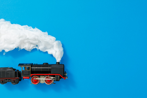 Toy steam locomotive from the 1930s with smoke from cotton on blue background cardboard