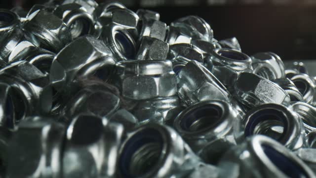Huge pile of silver nuts fasteners on black table