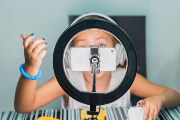istock Little girl behind a mobile phone held with a tripod and ring light. 1466636283