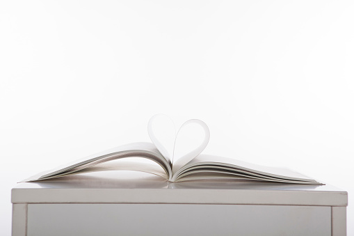 Some pages of a book formed into a heart on a white plain background