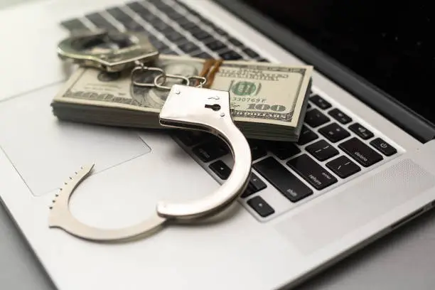 Photo of Handcuffs keyboard and dollars above
