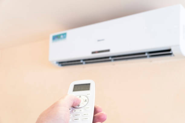 istock Hand with remote control directed on air conditioner. Climate control indoor concept 1466641241