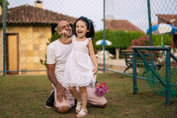 Father and daughter playing football in public park