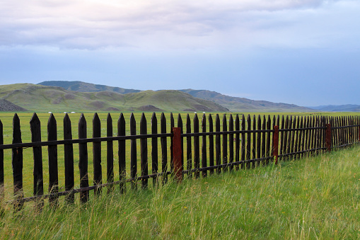 View of wooden fence and green landscape against sky, Amarbayasgalant Monastery, Mongolia.