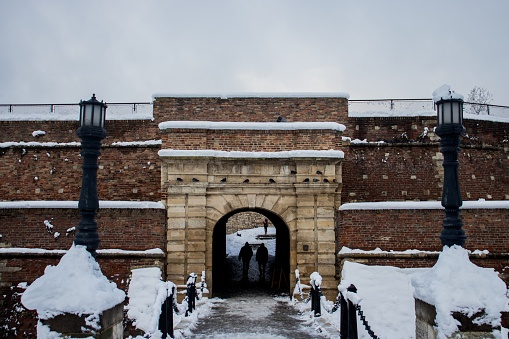 Roman wall 'muralla' covered with snow.  Lugo city, Galicia, Spain. Camino de Santiago, camino primitivo, pilgrimage route. Ancient arches in the foreground , row of modern apartment buildings in the background. UNESCO world heritage site both the \