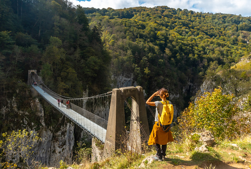 A young woman hiker observing the beautiful view of Passerelle d'Holzarte in Larrau, France