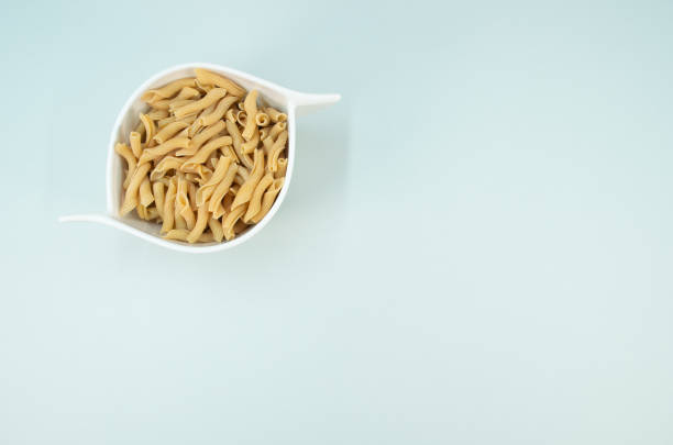 Top view shot of italian pasta in a canister on a light blue surface