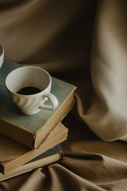 istock Vertical shot of a coffee cup on piled old books and beige fabric surface 1466646916