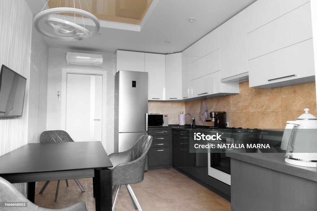 Minimalist kitchen interior with built-in electronics The kitchen in the apartment The design of the kitchen room. Black dining table in the kitchen. Gray kitchen interior with white cabinets. Built-in oven in the interior of the kitchen Kitchen interier American Culture Stock Photo