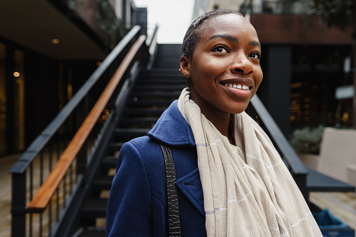 Portrait of smiling young black woman standing in the street close up