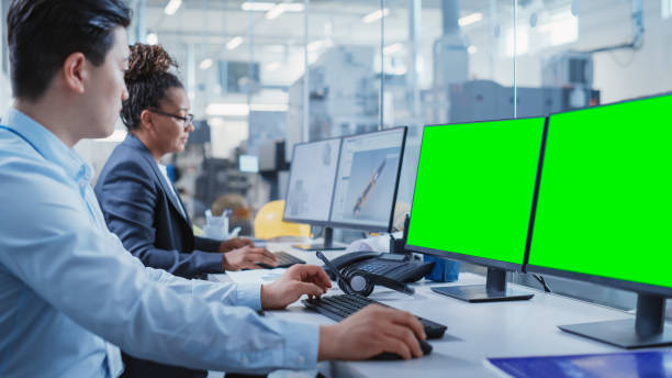 bureau d’usine: ingénieurs industriels dessinant des équipements schémas 3d d’une machine de l’industrie lourde sur un logiciel de cao informatique. un écran d’ordinateur est un modèle de maquette d’écran vert. - drafting computer graphic engineer plan photos et images de collection