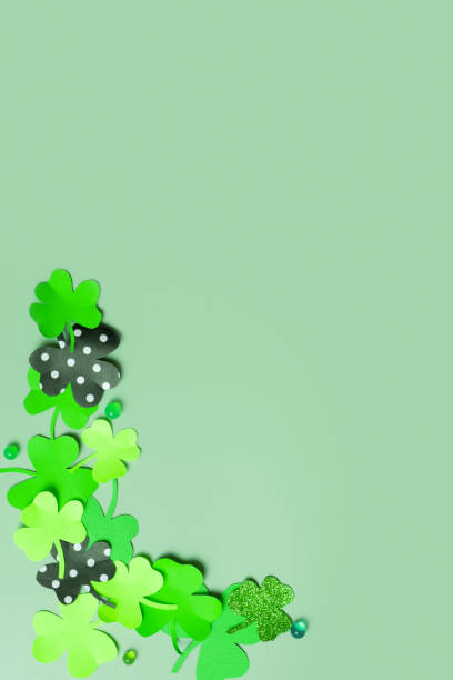 istock St. Patrick's Day minimalistic concept. Paper clover leaves on colored vertical background with copy space 1466654075
