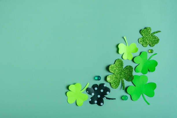 istock St. Patrick's Day minimalistic concept. Paper clover leaves on colored background with copy space 1466654078