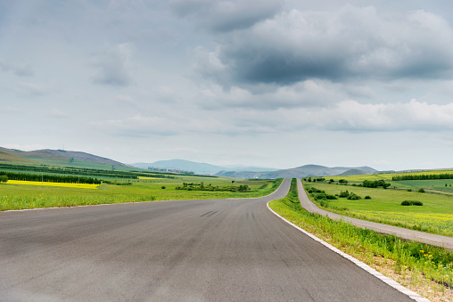 Empty asphalt road and green field.