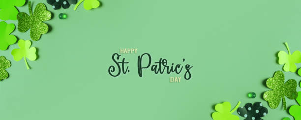 istock Happy St. Patrick's Day greeting text. Paper clover leaves on colored background banner format 1466654101
