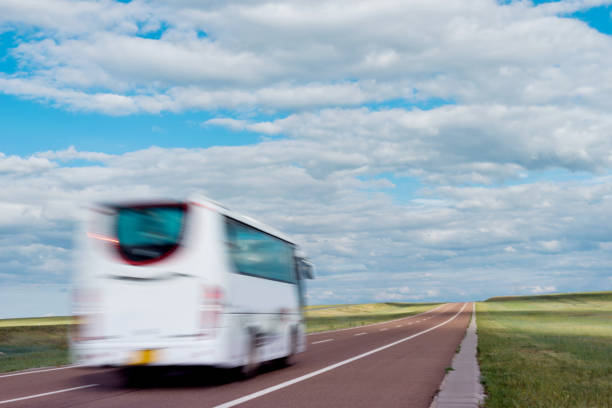 White bus driving through the prairie.
