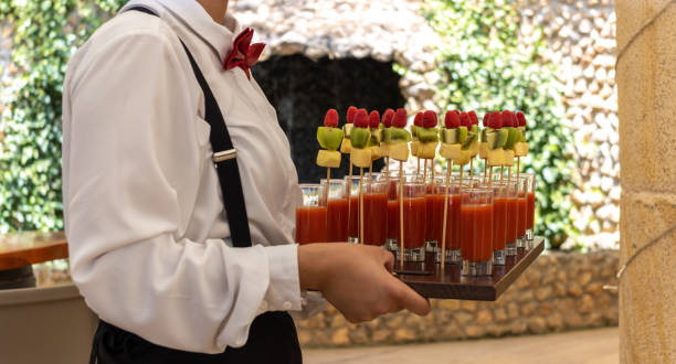 неузнаваемый официант, несущий деревянный поднос с фруктовыми коктейльными канапе на торжественном мероприятии - canape buffet cocktail food стоковые фото и изображения