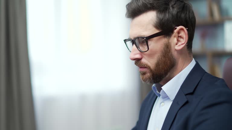 Busy mature business man investor with glasses typing on laptop computer working online at desktop in modern office