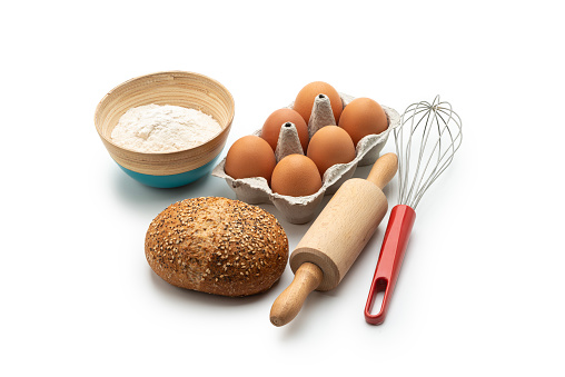 Baking ingredients, bread and kitchen utensils on white background