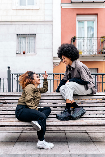 Stock photo of cool afro girls talking and looking at each other.