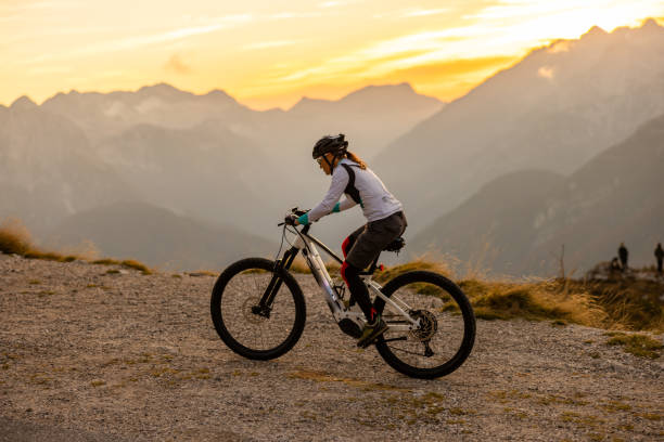 frau mit langen braunen haaren mit sonnenbrille und helm reitet den berg mangart hinauf. elektrofahrrad - recreational pursuit mountain biking nature outdoors stock-fotos und bilder