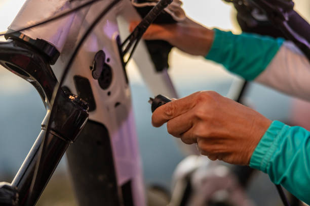 早朝に山の頂上で電動自転車を充電するためにケーブルを差し込む接写女性 - on wheels 写真 ストックフォトと画像