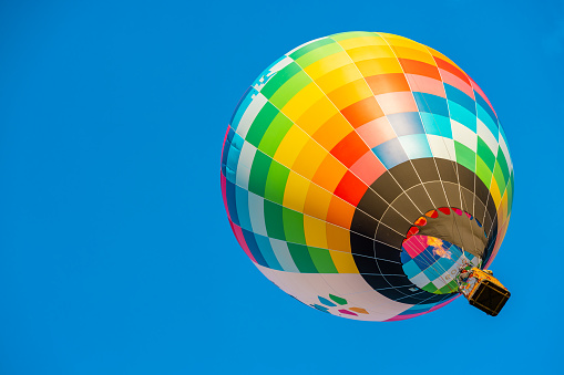 Balloons burning fuel as they fly over the city of Goreme in Cappadocia, with sightseeing tourists during a sunny summer day