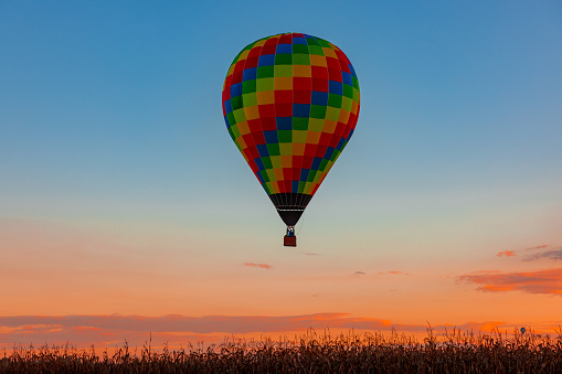 An Aerial View of a Multi-Colored Hot Air Balloon, Floating Over Pennsylvania Farmlands at Sunrise, on a Summer Day