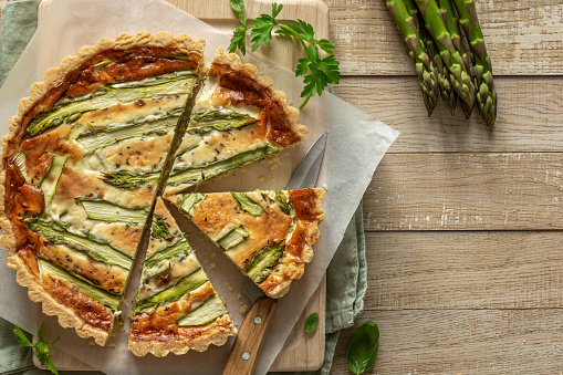 slices of savory asparagus tart on wooden background,  top view, copy space
