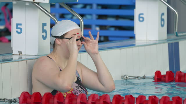 Young chubby woman, a professional swimmer, begins her swim and starts from the pool wall.