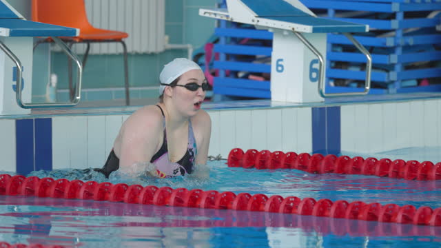 Young woman, a professional swimmer, starts from the wall of the pool and swims in a butterfly style
