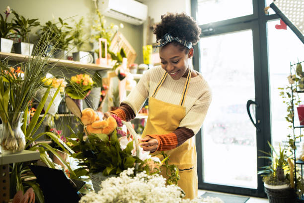 Young female florist Young florist works at her flower shop florist stock pictures, royalty-free photos & images