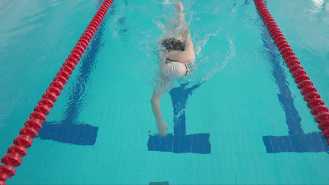 Young plump woman, a professional swimmer, swims in the crawl style.