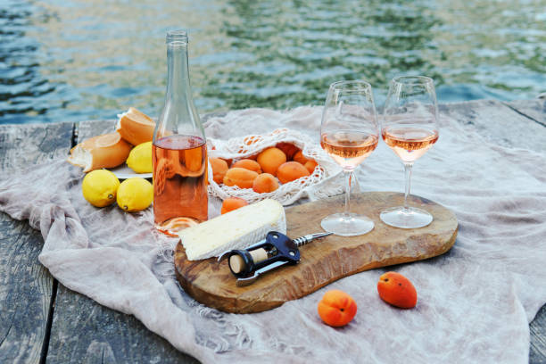 Rose wine, fruits and snacks on the wooden pier during picturesque picnic on the wooden dock stock photo