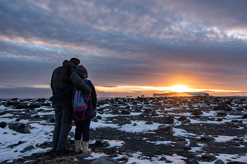 Couple affectionately embracing while enjoying a sunset in Iceland.